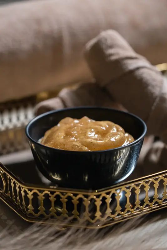 Golden honey scrub in a black bowl