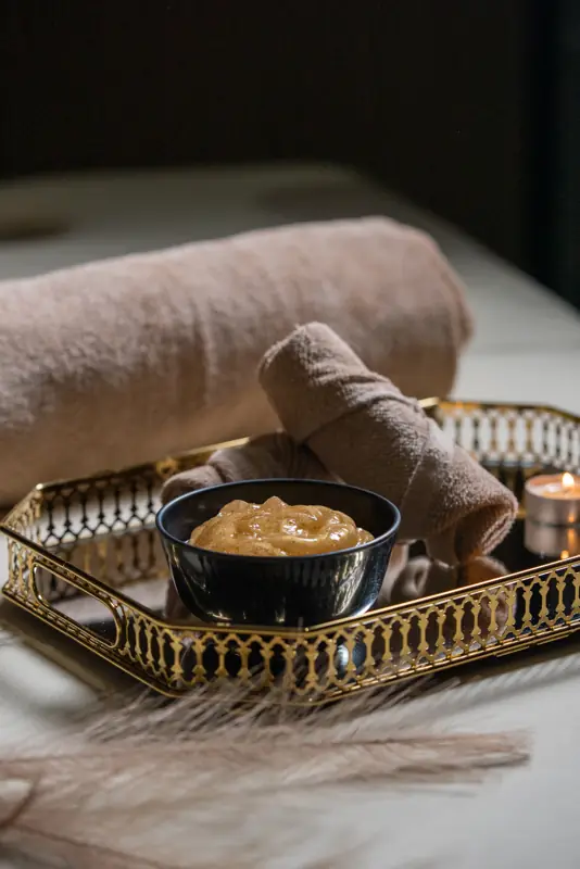 Honey scrub bowl and candles on a gold tray