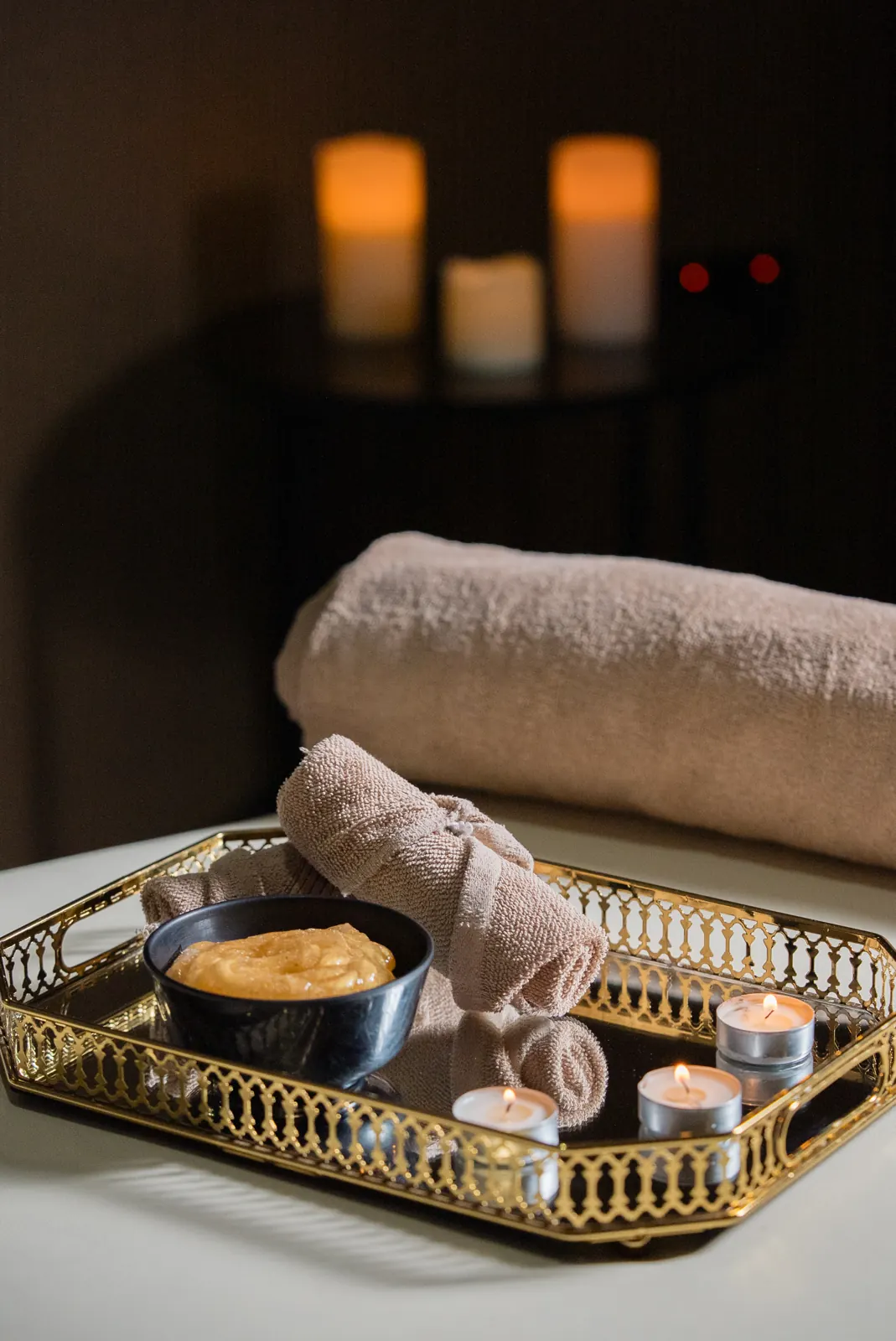 Candlelit spa setting with towel and gold tray